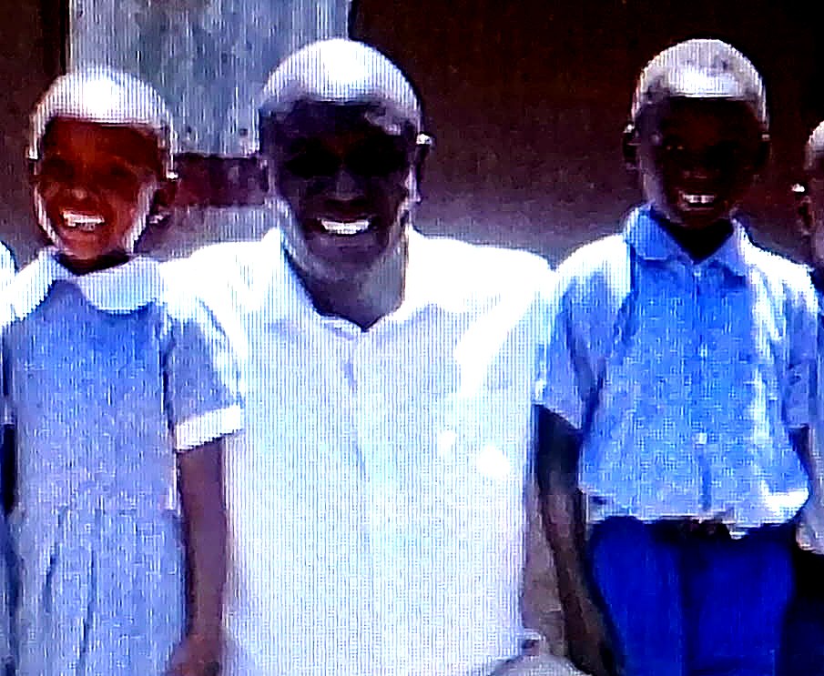 Local pastor with children outside a community school